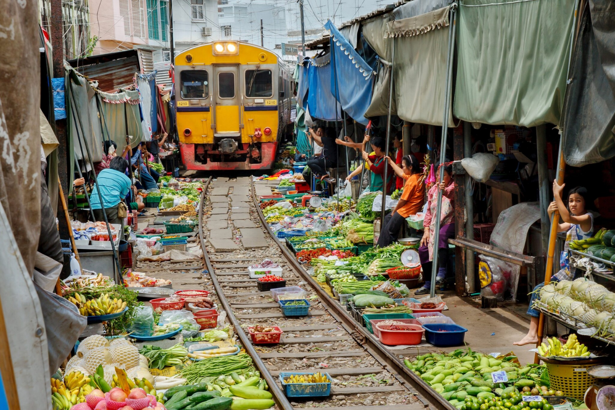 Vendors pulling back their stalls as a train passes through Maeklong Market